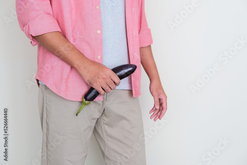 Cropped adult man holding eggplant in front of his pants