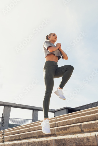 Woman jumping on steps and exercising against sky