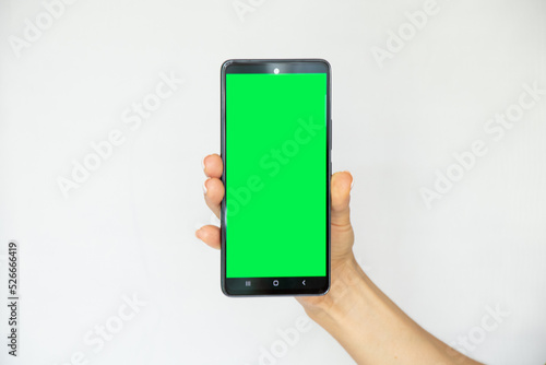 A girl on a white background in her hand holds a mobile phone with a green screen, a template with a phone, a green screen