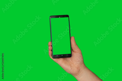 A man's hand on a green background holds a mobile phone with a green screen, a template with a phone, a green screen