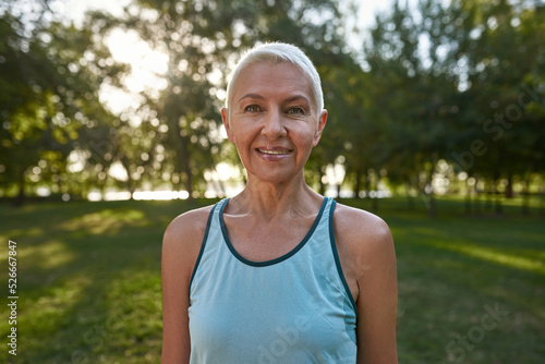 Sportive caucasian senior woman in blur green park