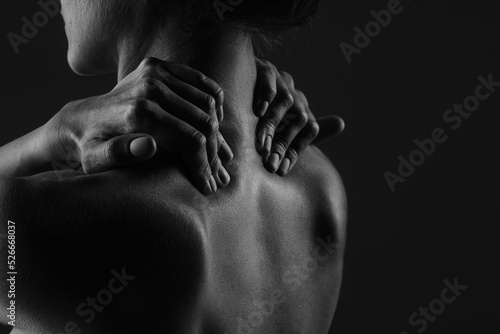 a girl makes herself a massage of her neck with her hands close-up on a dark background  the concept of treatment of the neck and spine