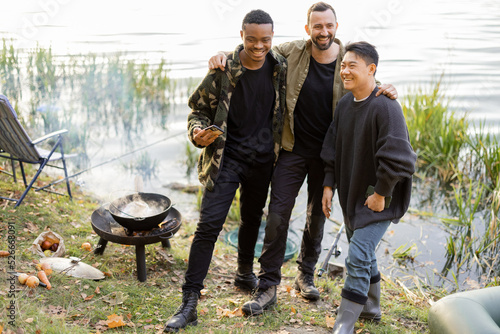 Portrait of three multiracial male friends having fun, standing together at picnic while fishing. Concept of friendship, spending time together and bonding on outdoor pursuits