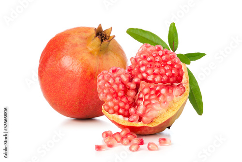 a whole pomegranate fruit with seeds and green leaves on white background.
