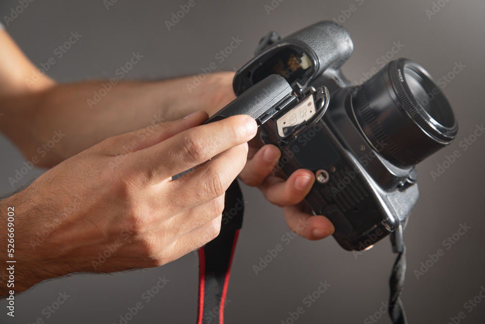 Photographer inserting battery to the camera. Photographer inserting battery to the camera.
