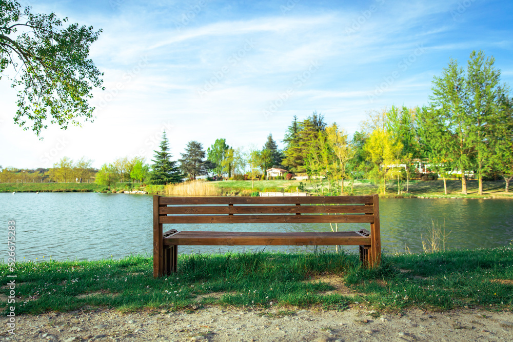Empty wooden bench in front of lake at park Empty wooden bench in front of lake at park
