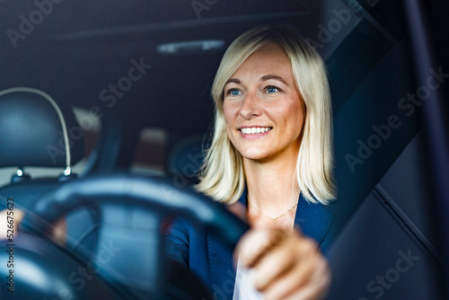 Smiling businesswoman driving car seen through windshield photo