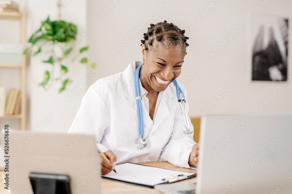 Happy doctor talking on video call through laptop at home office Happy doctor talking on video call through laptop at home office