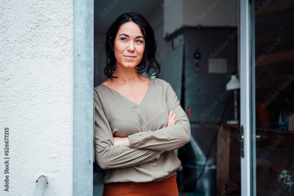 Smiling woman standing with arms crossed at doorway Smiling woman standing with arms crossed at doorway