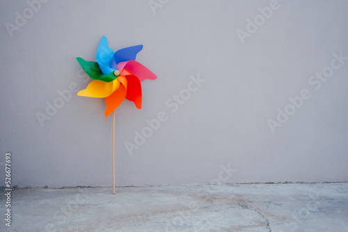 Multi colored pinwheel toy in front of gray wall photo