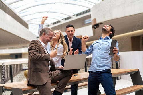 Happy business colleagues celebrating good news in office corridor