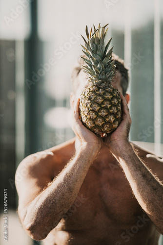 Man covering face with pineapple photo