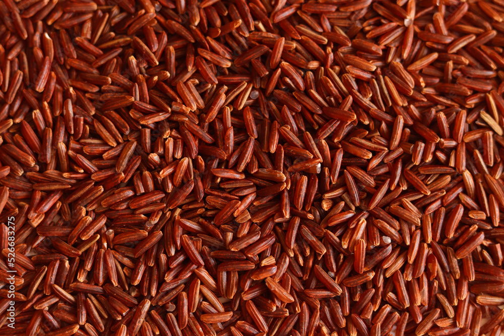 Dry uncooked brown wild rice as a background . Red grains, a stack of cereals. Organic natural ingredient for a healthy food.