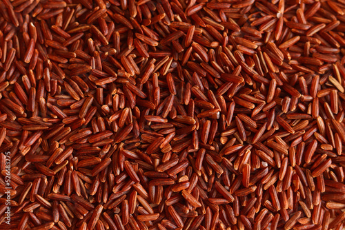 Dry uncooked brown wild rice as a background . Red grains, a stack of cereals. Organic natural ingredient for a healthy food.
