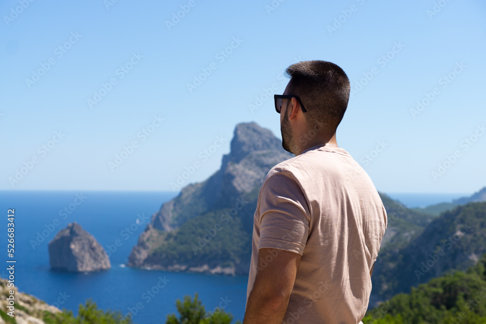 Young male tourist on his back looking at the Mediterranean Sea in Mallorca, Spain.