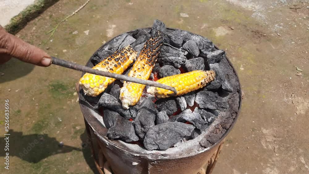 Grilled corn cobs on coal stove. Fresh roasted corncobs on coal fire