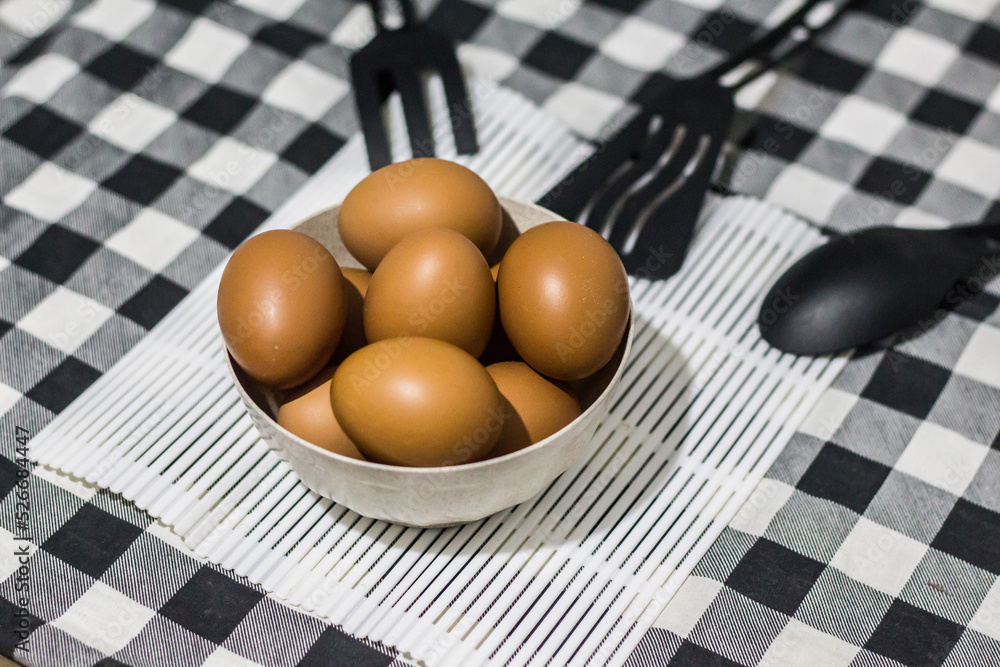 Brown eggs in bowl on a black and white fabric tablecloth texture background with copy space. Selective focus Brown eggs in bowl on a black and white fabric tablecloth texture background with copy space. Selective focus