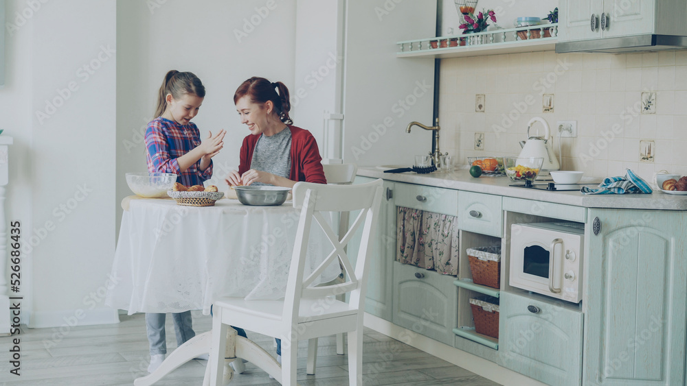 custom made wallpaper toronto digitalSmiling mother and cute funny daughter making cookies together using dough while sitting in modern kitchen at home. Family, food and people concept