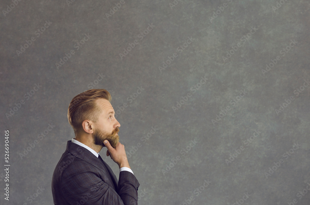 Thinking puzzled confused uncertain businessman looking forward at grey studio copy space. Side view shot. Executive manager or company leader entrepreneur searching problem solution issue answer Thinking puzzled confused uncertain businessman looking forward at grey studio copy space. Side view shot. Executive manager or company leader entrepreneur searching problem solution issue answer