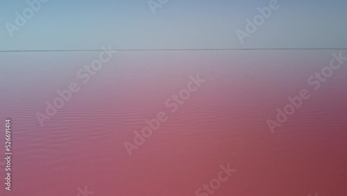 Flying over a pink salt lake. Salt production facilities saline evaporation pond fields in the salty lake. Dunaliella salina impart a red, pink water in mineral lake with dry cristallized salty coast photo