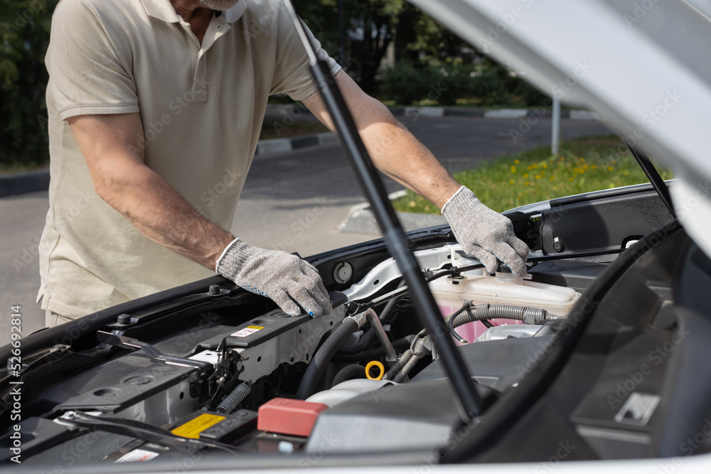 man opens cap of expansion tank in car man opens cap of expansion tank in car