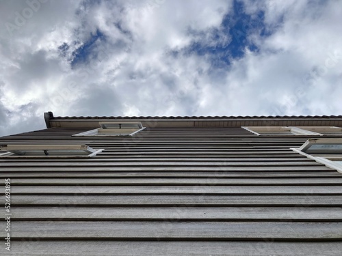 Wallpaper Mural View into the cloudy sky along a wooden facade of a building with windows Torontodigital.ca