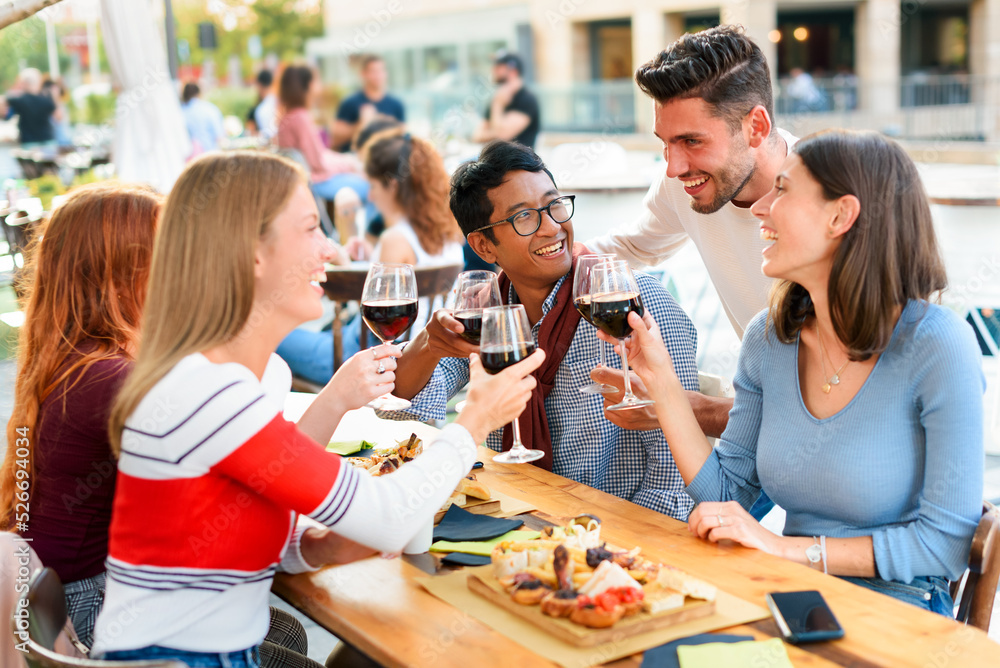 Diverse friends hanging out in outdoor pub drinkin wine