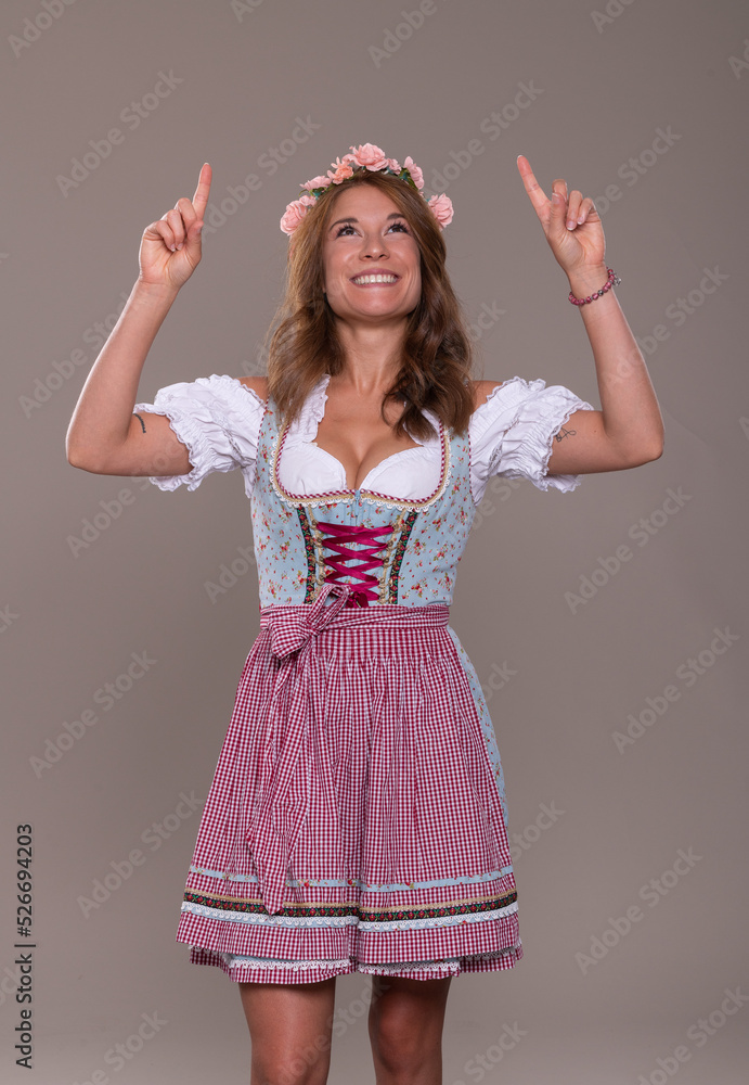Junge Frau im Dirndl Kleid zeigt nach oben Junge Frau im Dirndl Kleid zeigt nach oben