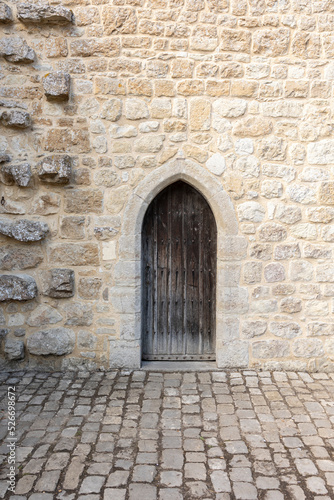 medieval castle wooden door, stone wall and cobbled floor, verical format