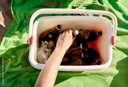 Crop woman taking beer from cooler photo