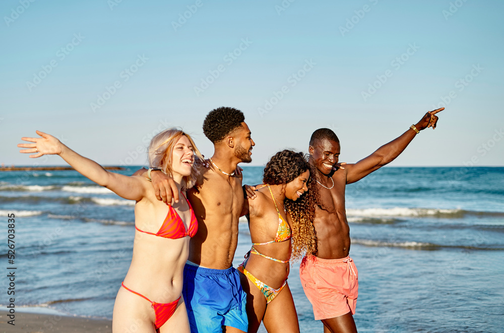 Diverse friends hugging and walking near sea Diverse friends hugging and walking near sea