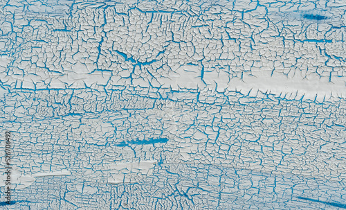 The texture of cracked paint. White texture with a craquelure effect on a blue background
