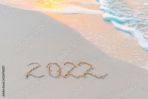 handwritten inscription 2022 on the sand by the sea on Maldives island