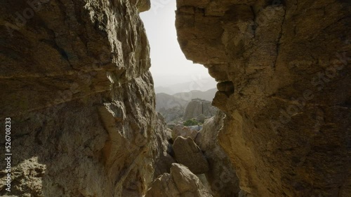 Hole in rock layered slate looking over canyon valley mountain range. Foggy southern cliffside perspective shot. Shot on 5k RED GEMINI. Mount Lemmon, Arizona United States photo