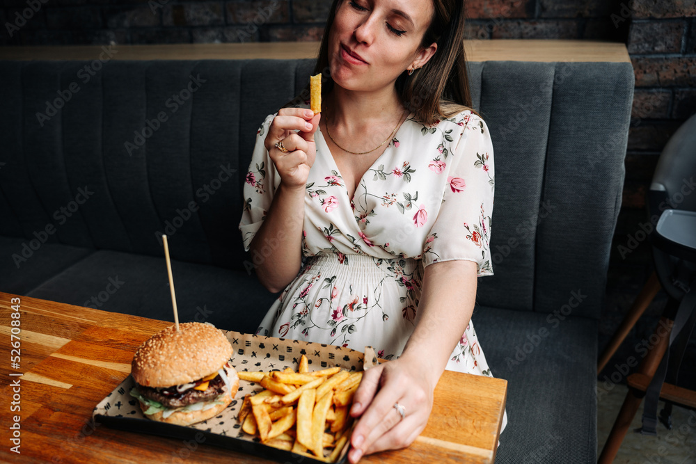 Fast food burger eat pregnant girl. Pretty young happy pregnancy woman eating tasty hamburger