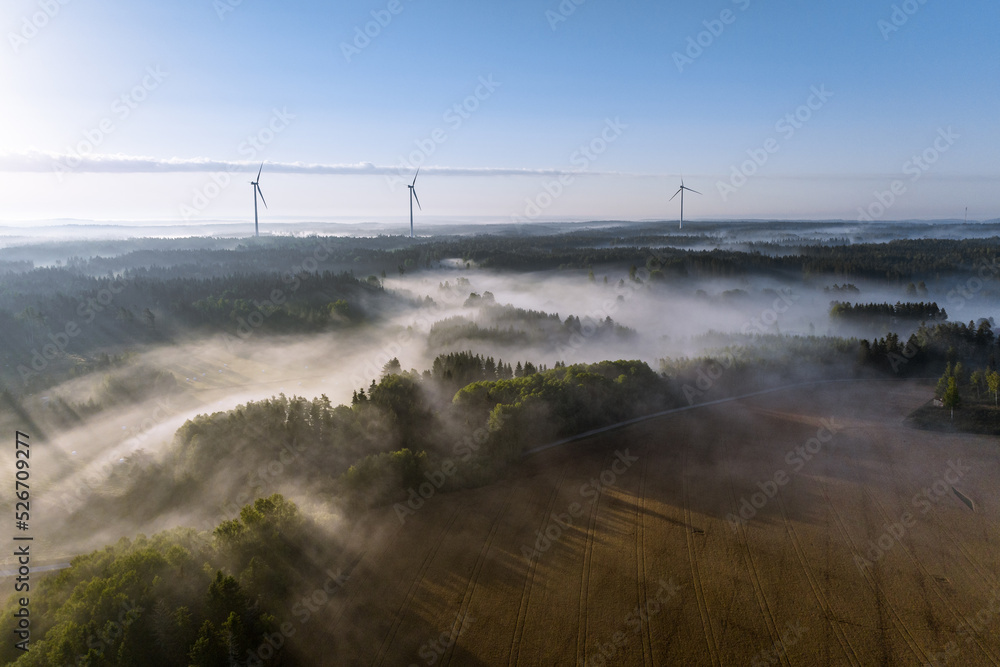 Wind energy mills at dawn in misty landscape in Finland