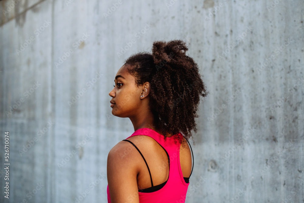 Rear view of young mulitiracial girl standing in front of city concrete wall. Rear view of young mulitiracial girl standing in front of city concrete wall.