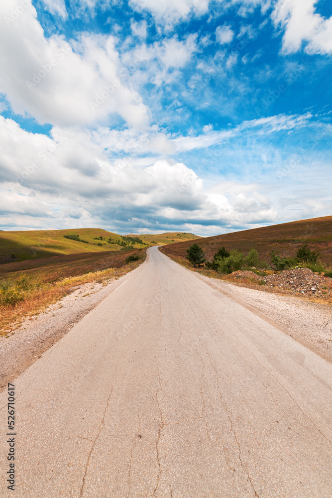 Empty asphalt road through beautiful Zlatibor region landscape stretching in diminishing perspective and disappearing behind the green hill of this famous Serbian tourist resort