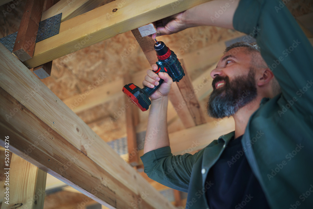 Construction worker working with screwdriver on wooden frame, diy eco-friendly homes concept. Construction worker working with screwdriver on wooden frame, diy eco-friendly homes concept.