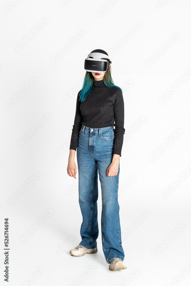 Virtual reality. A teenage girl with blue hair wearing virtual reality glasses watches movies or plays video games, isolated on a white background. A cheerful girl looking at VR glasses Virtual reality. A teenage girl with blue hair wearing virtual reality glasses watches movies or plays video games, isolated on a white background. A cheerful girl looking at VR glasses