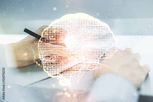 Creative artificial Intelligence concept with human brain hologram and hand writing in notebook on background with laptop. Multiexposure © Pixels Hunter