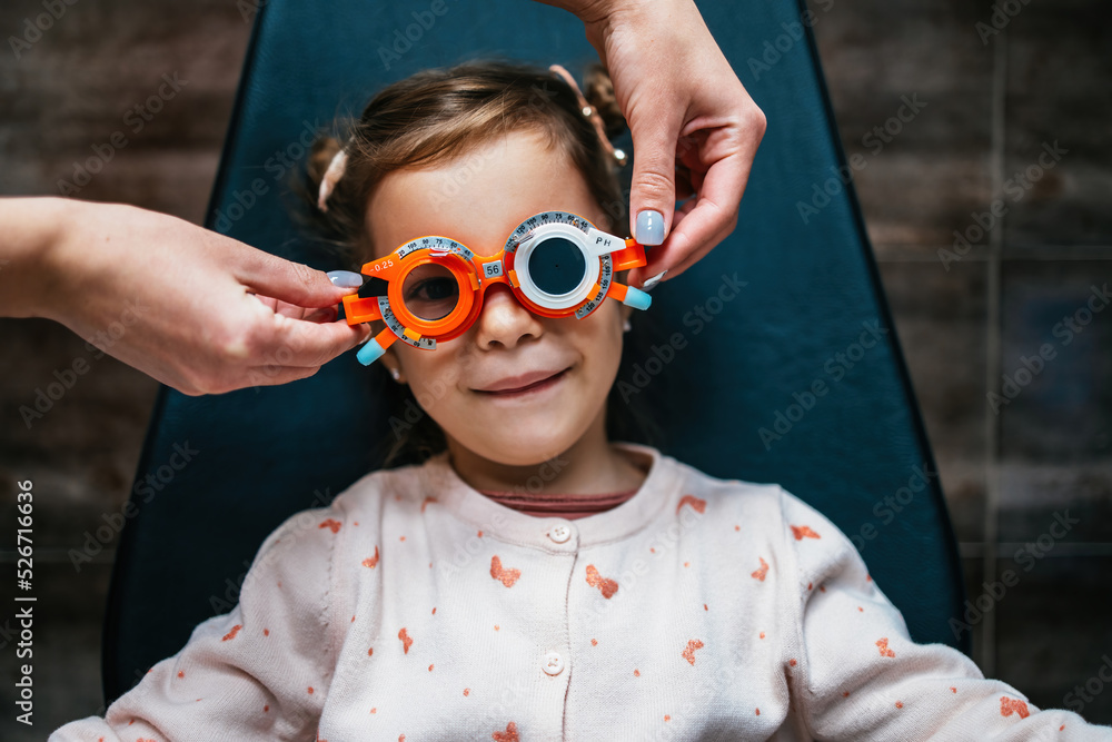 Optometry Cute Beautiful and adorable little girl with optometry glasses receiving ...