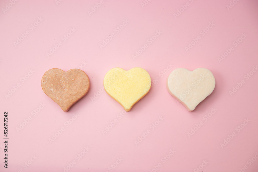 Heart shaped pink bar of soap on a light pink background. Top view, copy space. Heart shaped soaps. Importance of personal hygiene care. Copy space.