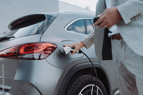 Man holding power supply cable at electric vehicle charging station, closeup