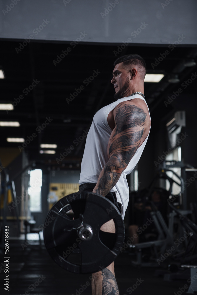Vertical profile shot of a big muscular bodybuilder lifting heavy barbell Vertical profile shot of a big muscular bodybuilder lifting heavy barbell