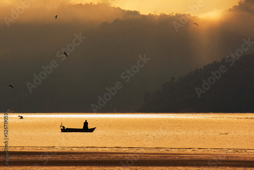 Vista para a baia de Paraty ao nascer do sol, silhoueta de pescadores e passaros com o amanhecer dourado photo