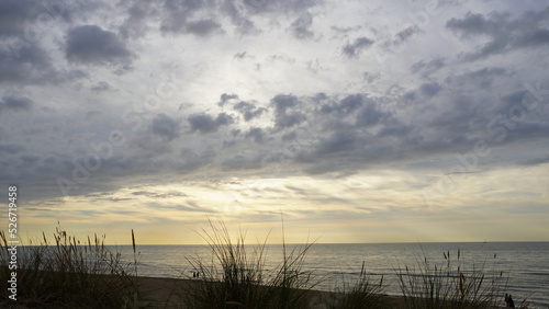 Fototapeta Naklejka Na Ścianę i Meble -  Dünengras mit Blick auf das Meer und dramatischen Sonnenuntergang mit dunklen Wolken 