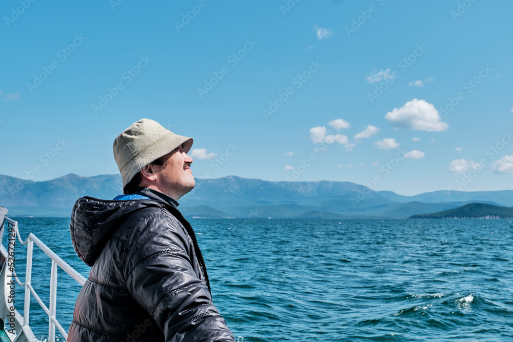 Mature asian man as tourist on boat trip. Chivyrkuisky Bay of Lake Baikal, Russia.