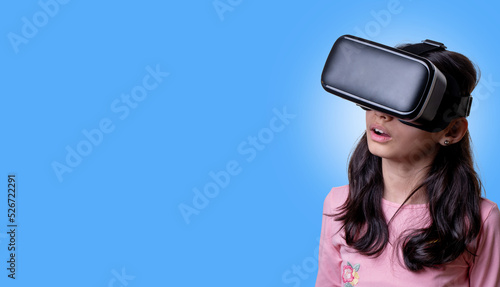 VR glasses , little girl with virtual reality headset. Innovation technology and education concept. Funny girl using a virtual reality headset isolated on blue  background © Нигяр Гусейнова