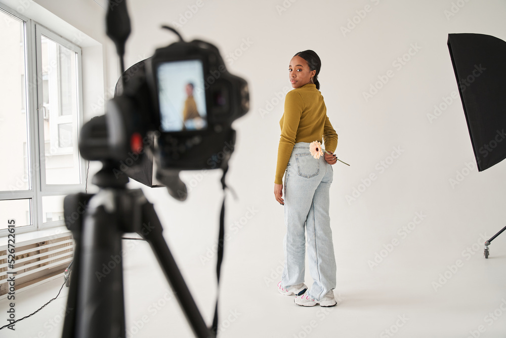 Multiracial professional model standing with camomile at the studio and posing to the camera Multiracial professional model standing with camomile at the studio and posing to the camera